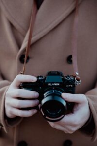 Close-up of a person holding a vintage Fujifilm camera, conveying nostalgia.