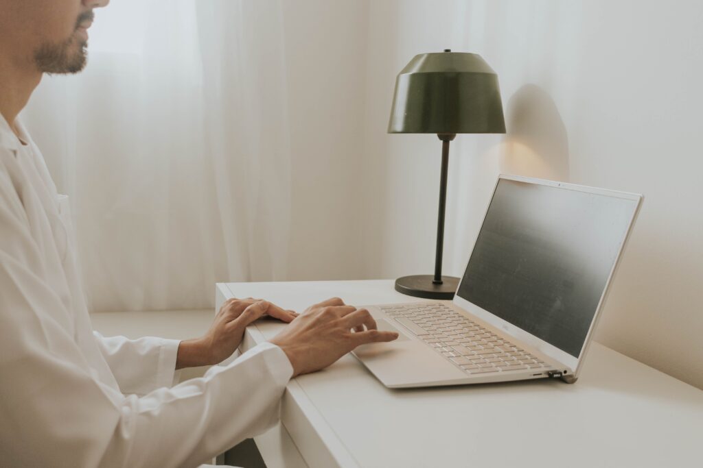 A man in a home office setting working on a laptop at a desk with a lamp, exuding a minimalist vibe.